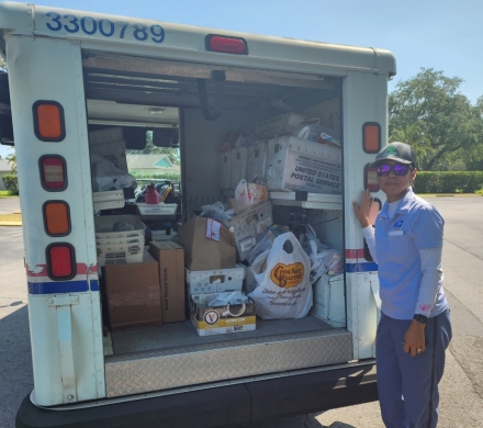 letter carrier with donated food for Stamp Out Hunger